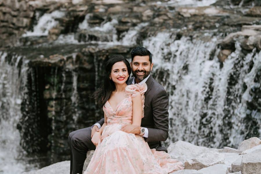 Couple Sitting On Rocks Near A Waterfall Smiling For Dallas Family Photographer