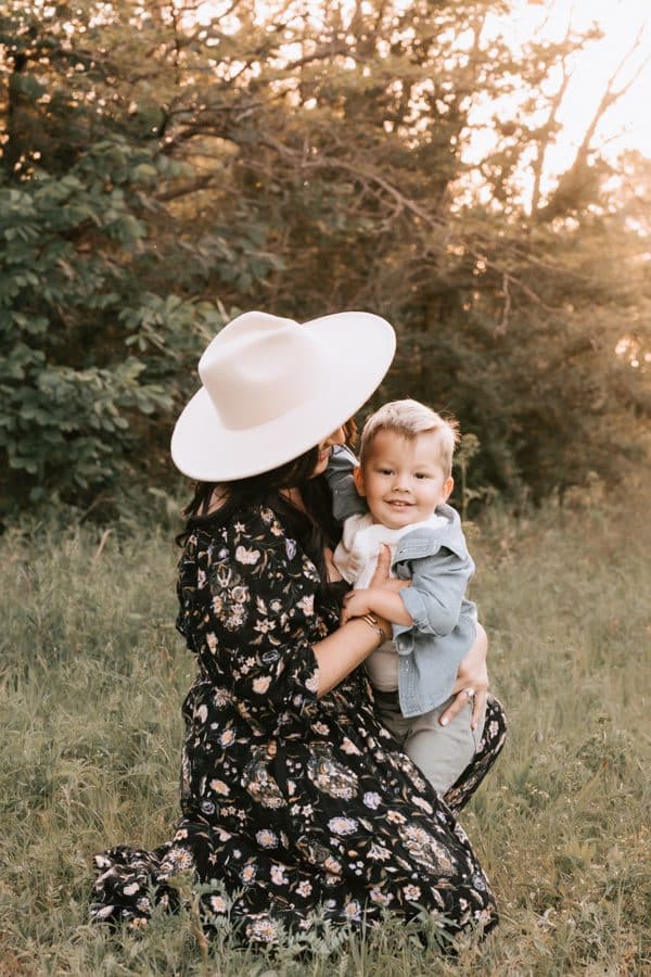 Family Photographed With Mother Smiling At Young Son While Sitting On Grass For Dallas Family Photography
