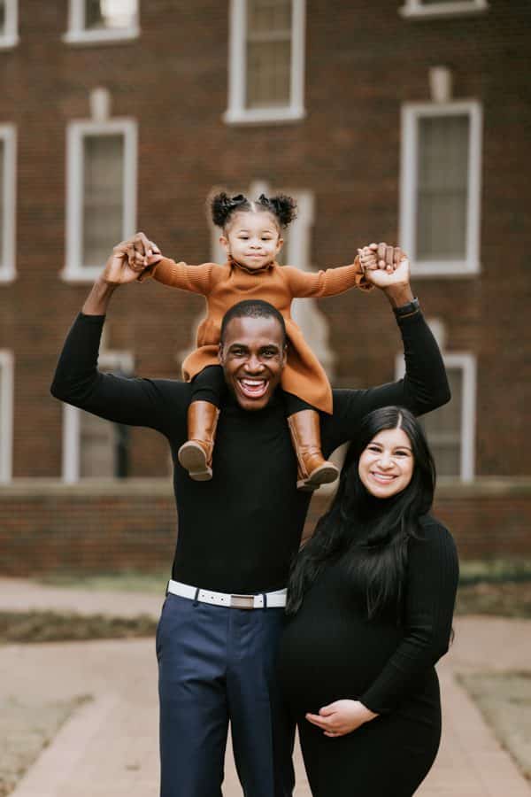 father holding daughter on shoulders while mom is smiling during a family photoshoot in dallas