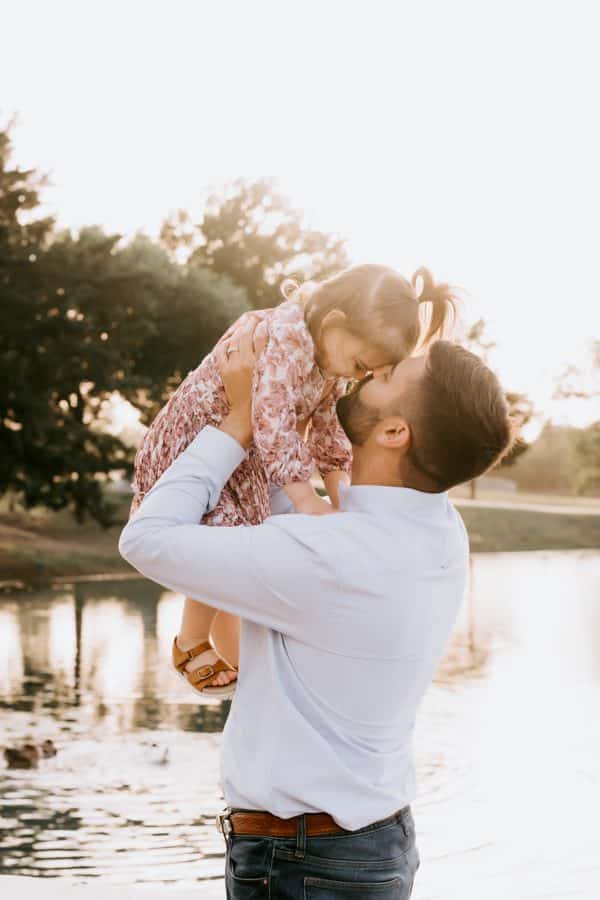 father holding up baby girl kissing her on cheek for a dallas family photoshoot