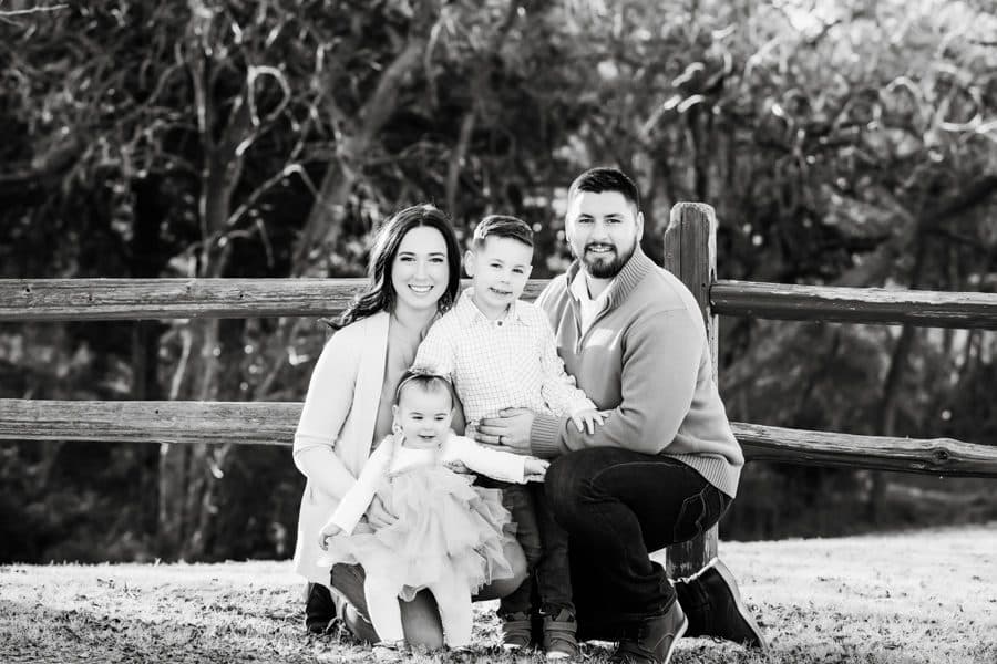 Black And White Family Photo With Everyone Pose On Grass Smiling For Family Photographer Dallas