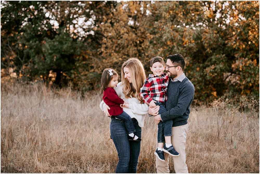 Family Of Four Embracing In An Autumnal Field With Professional Photographer In Dallas