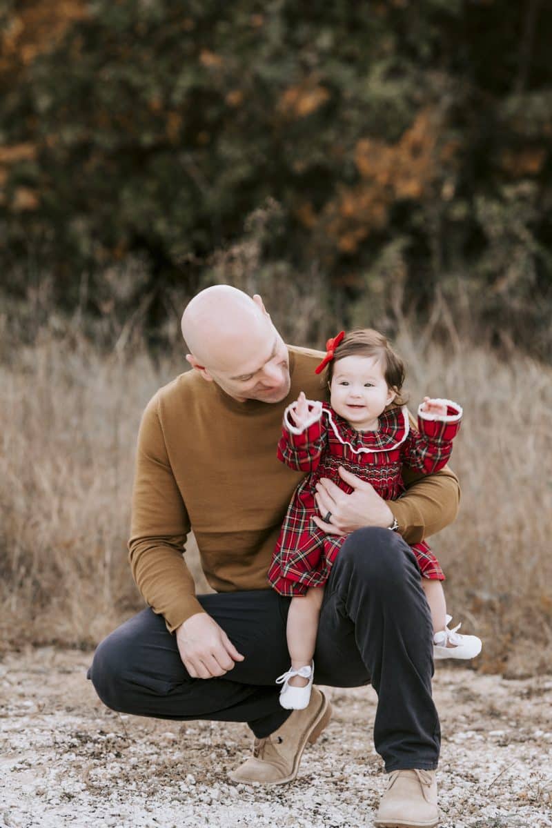 Father Holding Child Outdoors While Booking A Family Photo Session