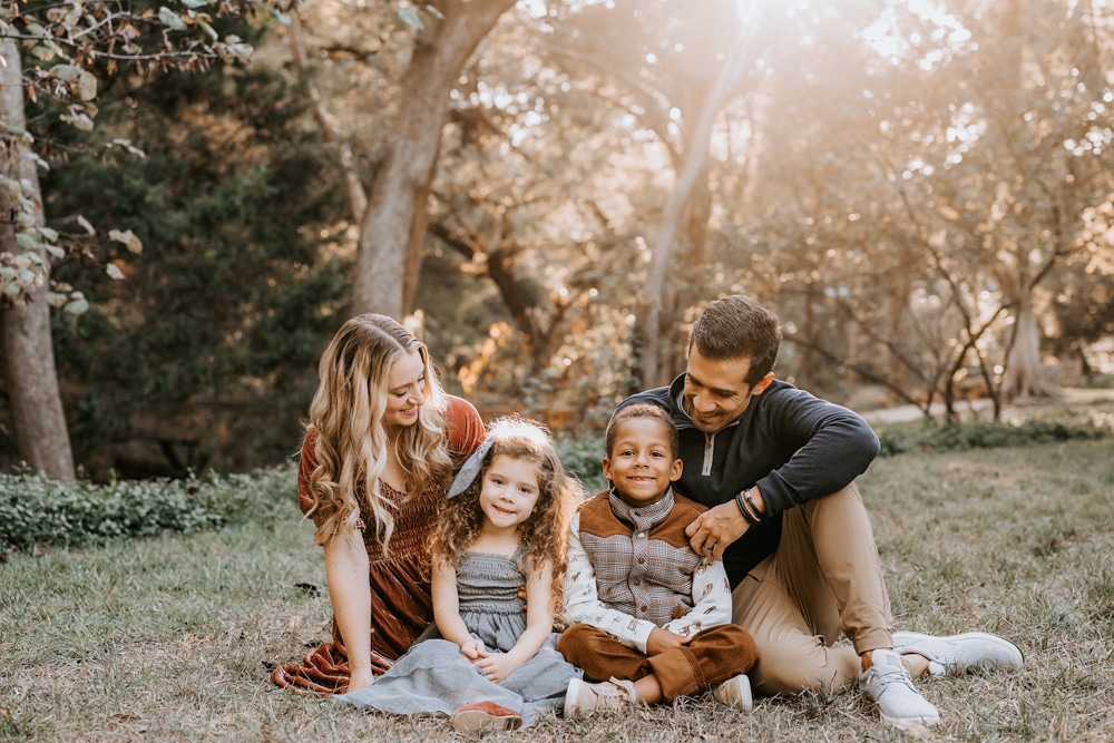 family of four sitting on grass in a park for a dallas family photography