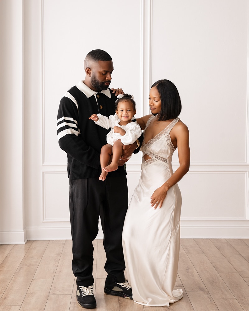 parents pose with baby girl smiling at camera for dallas family photographer