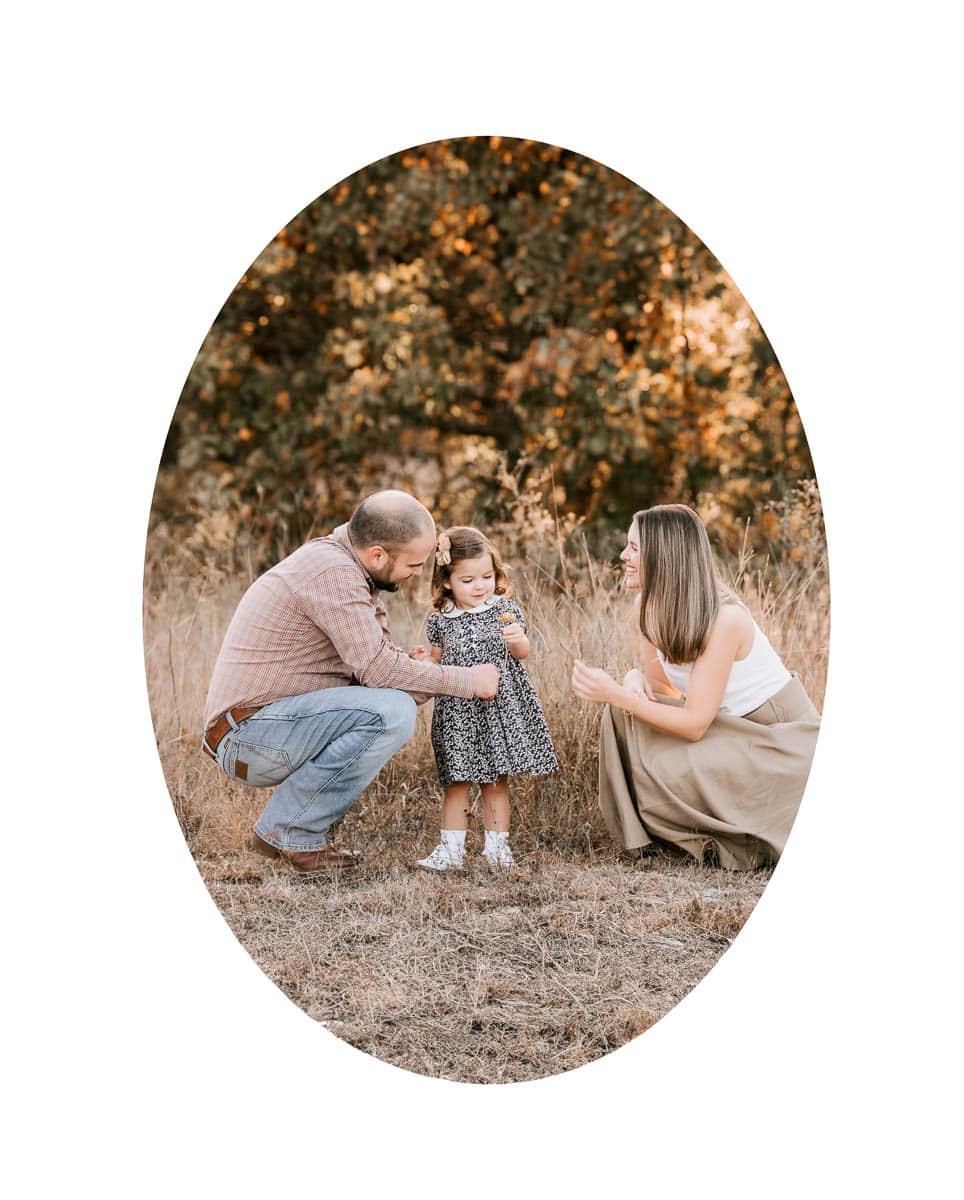 Outdoor family photography session in Dallas featuring parents and toddler in a natural field setting